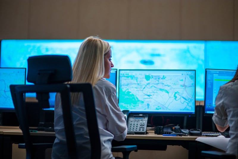 Operations staff monitoring logistics data on multiple screens in a control room. 