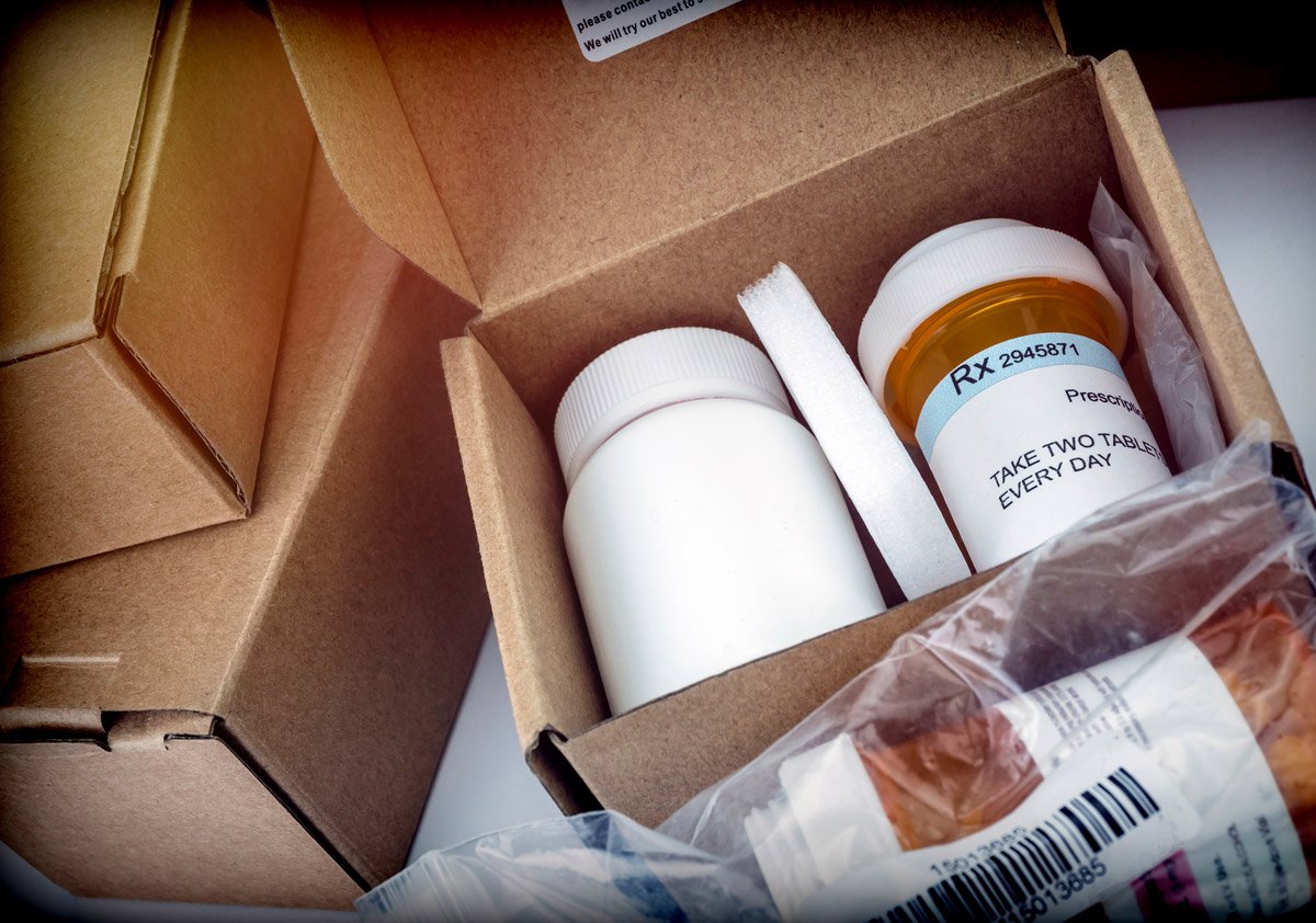 Open cardboard box containing prescription medication bottles with labeled instructions, packaged for delivery. 