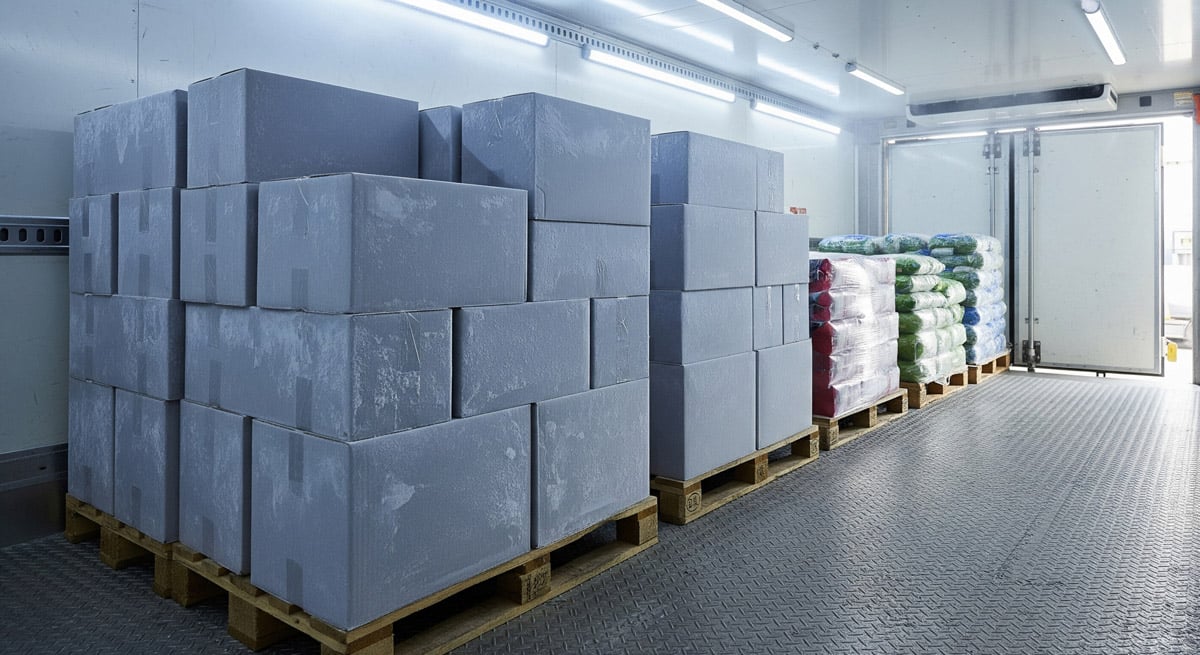 Pallets of insulated containers and packaged goods stored inside a refrigerated warehouse or cold storage facility. 